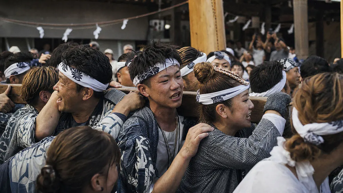 Fotografía editorial de una celebración popular en Japón: varias personas participan en una fiesta comunitaria y llevan hachi